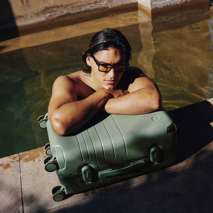 A man rests poolside with the Hybrid Carry-On in Mint, soaking up the sun and stillness.